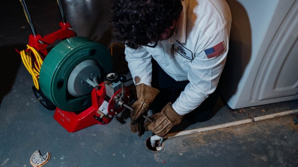 A man is engaged in repairing a pipe with a tool, demonstrating skilled craftsmanship.